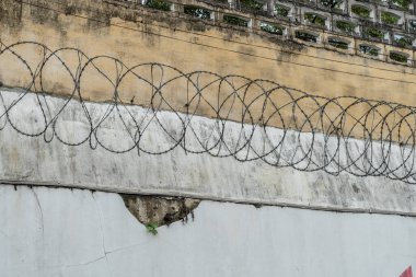 Hapishanenin beton duvarı dikenli telle kaplı.