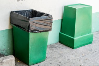 Beton duvar arka planında yeşil çöp kutusu
