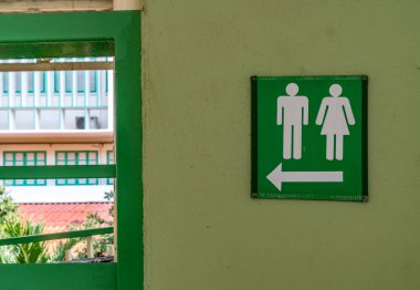 Tuvalet etiketi yeşil beton duvarda.