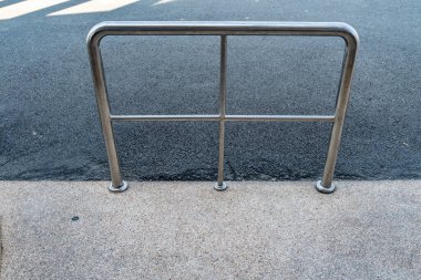 Beton zeminde asfalt yol arka planında paslanmaz parmaklıklar var.