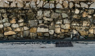 Beton yolda metal kaplamalı taş çit.