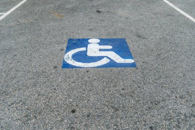 Otoparktaki asfalt yolda engelli işareti.
