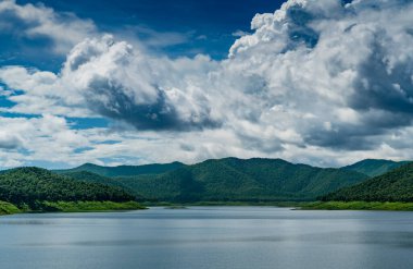 Dağlı, beyaz bulutlu ve mavi arkaplanlı göl