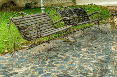 Bahçede beton zeminde ahşap park bankı