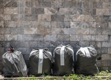 Kaldırımda siyah çöp torbası ve mermer duvar çiti
