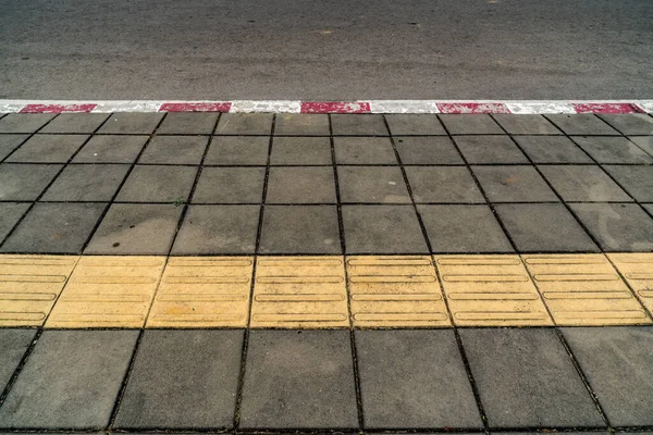 アスファルト道路と赤と白のコンクリート縁石とコンクリートブロック歩道 — ストック写真