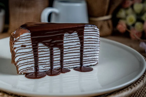 ホワイトセラミックプレートにチョコレートクレープケーキのピース — ストック写真