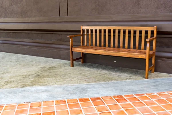 Wood park bench on concrete floor with brown concrete wall