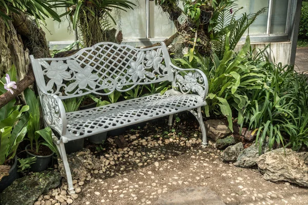 Metal park bench on concrete floor in garden