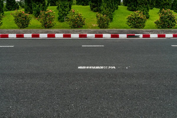 Asfalt Väg Med Röd Och Vit Betong Trottoarkant Och Gröna — Stockfoto