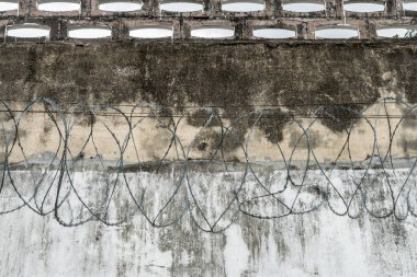 Hapishanenin beton duvarı dikenli telle kaplı.