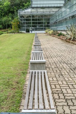 Beton zeminde ahşap park bankında parktaki yeşil evin bir kısmı