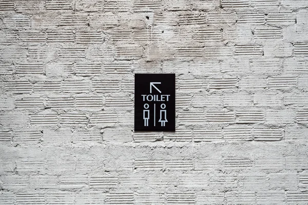 コンクリートレンガの壁にトイレのモダンな看板ラベル — ストック写真