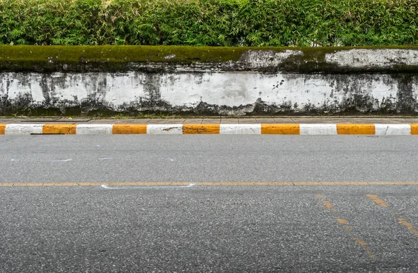 人行道路边有黄白两色交通标志的沥青路面和旧的白色混凝土围栏 — 图库照片