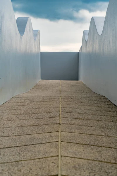 Concrete ramp for wheelchair with white concrete railing