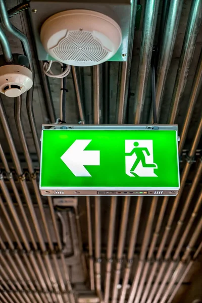 Green Emergency exit sign with metal pipes