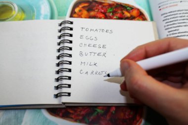 Tarife göre yemek pişirmek için alışveriş listesi yazıyorum. Gıda alışveriş konsepti.