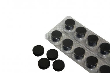 Beyaz arka planda izole blister paketi aktif kömür hapları.