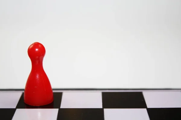 Solitário único ludo vermelho figura peça no tabuleiro de xadrez com fundo branco vazio — Fotografia de Stock