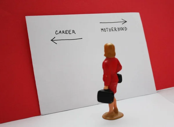 Miniature people, woman decides between a career and a child. Bilogical clock, feministmambitions, job or family dilemma conceptual photo.