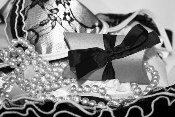 Black and white gift little box with dark bow and lacy lingerie and beads. — Stock Photo, Image