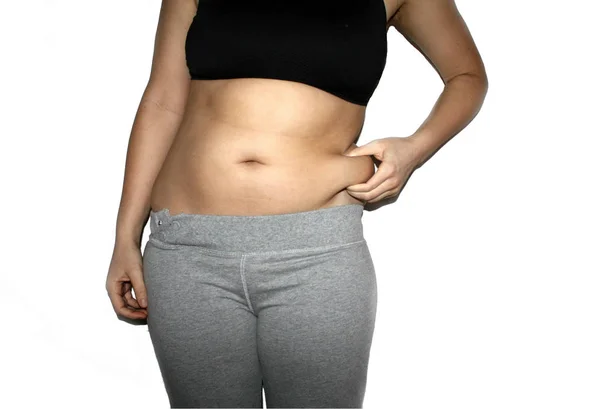 Mano de mujer sosteniendo su propia grasa del vientre aislada en blanco. Concepto de pérdida de peso . — Foto de Stock