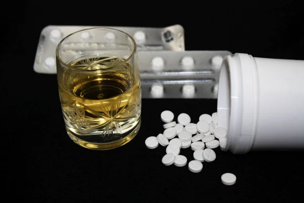 Glass of alcohol, alcoholic drink and some white pills — Stock Photo, Image