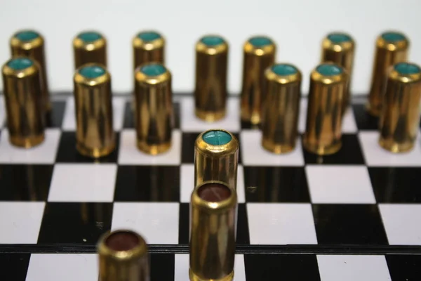 Латунні кулі на боєприпасах на чорно-білому шаховому столі — стокове фото