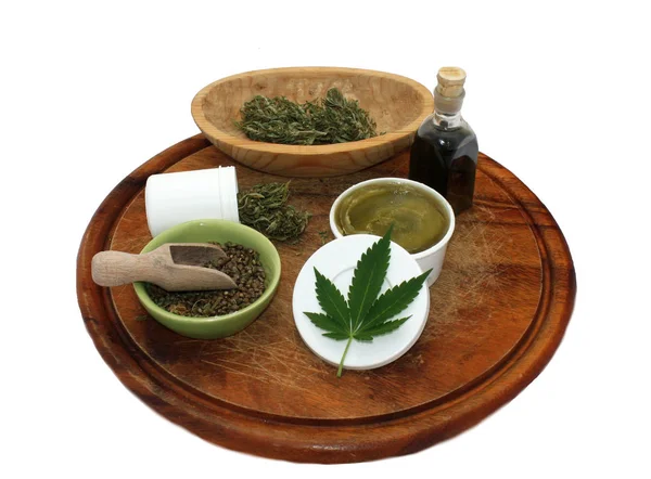 Marijuana products, cannabis tincture, dry weed buds, seeds, hemp salve on wooden desk isolated on white — Stock Photo, Image