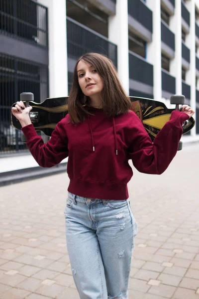 Bir kız kocaman gözleri ve onun kollarında Bordo kapüşonlu bir longboard