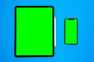 iPad ve iPhone, bir kalem ile mavi arka planda yeni tablet, ve yeşil ekran üst görünümü