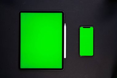 iPad ve iPhone, bir klavye ve kalem ile siyah arka planda yeni tablet, ve yeşil ekran üst görünümü