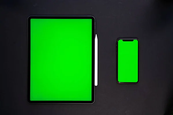 iPad ve iPhone, bir klavye ve kalem ile siyah arka planda yeni tablet, ve yeşil ekran üst görünümü