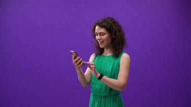 Kıvırcık kız mor bir arka planda iPhone 11pro 'da oyun oynuyor.