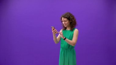 Kıvırcık kız mor bir arka planda iPhone 11pro 'da oyun oynuyor.