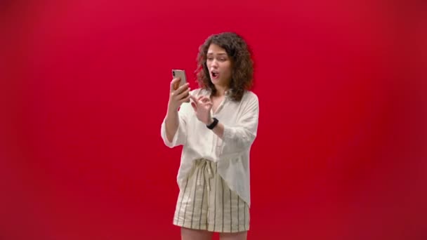 Kudrnaté Dívka Hraje Hry Iphone 11Pro Ruce Červeném Pozadí — Stock video