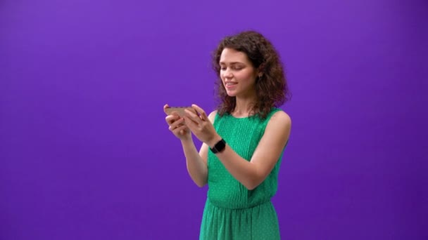 Кудрявая Девушка Играет Игры Iphone 11Pro Руке Фиолетовом Фоне — стоковое видео