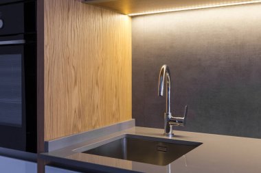 Undermounted bir lavabo ve bir mikser modern loft mutfak ahşap detayları ile gri renkli bir taş seramik tezgah monte. 