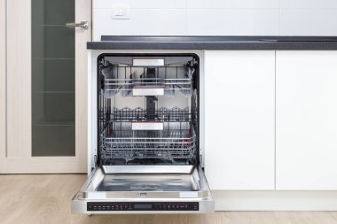 Build-in dishwasher with opened door in a white kitchen clipart