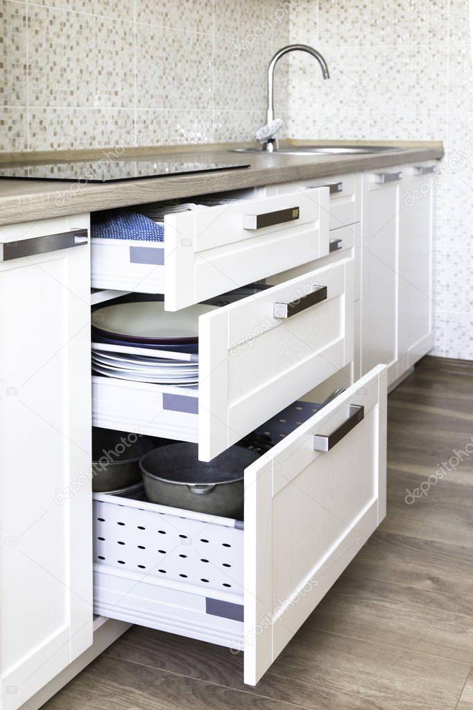 Opened kitchen drawers with plates inside, a smart solution for kitchen storage and organizing. 