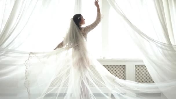 4k krásná a krásná nevěsta ve svatebních šatech. Zůstaňte poblíž okna se závěsy
