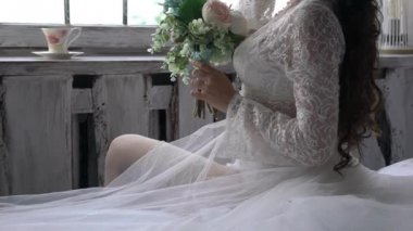 Elbise giymiş, elinde çiçeklerle oturan genç bir kız.