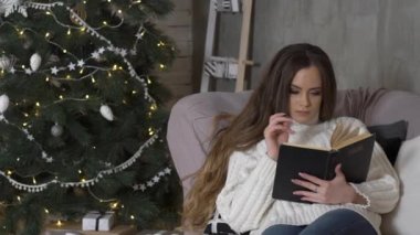 Sevimli kadının önünde Noel ağacı kitap okuma