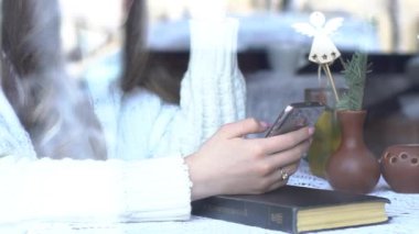 Kafede, akıllı telefon kullanan güzel genç kadın pencereden görünümü