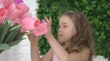 Sarı saçlı kız ve çiçekler lale, güller, yeşil bir arka planda bir demet