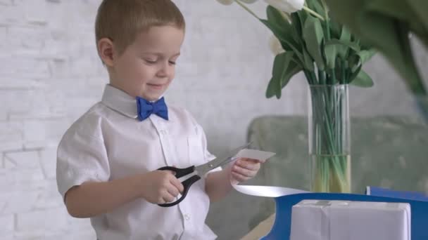 Chłopiec Dekorowanie Owinięte Gift Box Białą Wstążką — Wideo stockowe