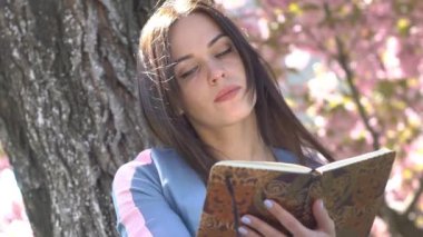 Güzel kız Sakura Inanılmaz renk altında bir kitap okur