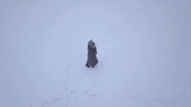 4K Smooth Spiral Aerial Footage Of Young Blonde Girl Walking Through Snow.