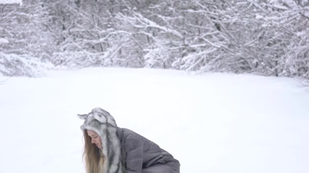 冬の季節の美しいブロンドの女の子は雪で遊んでいます — ストック動画