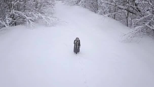 平滑螺旋空中镜头的年轻金发女孩走过雪 — 图库视频影像